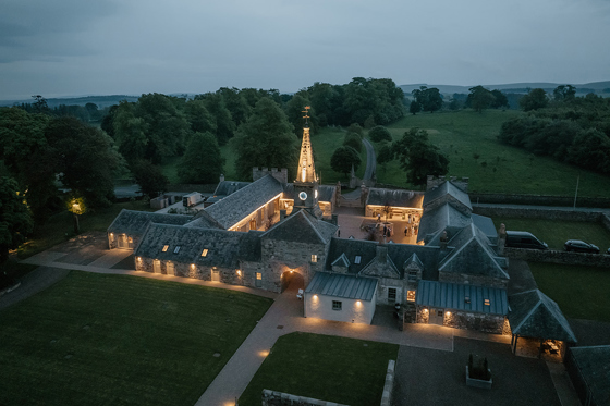 Aerial evening view of illuminated Rosebery House wedding venue and courtyard in Midlothian