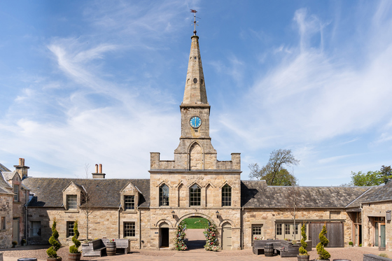 Historic stone entrance and clock tower at Rosebery House exclusive-use wedding venue in Scotland