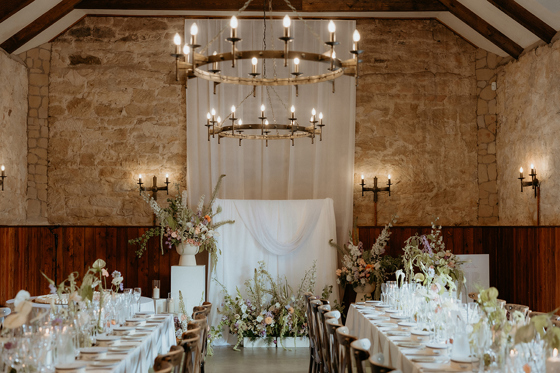 Long banquet tables with floral styling inside rustic stone reception space at Rosebery House
