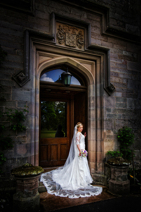 Bride poses at arched door of SCHLOSS Roxburghe.