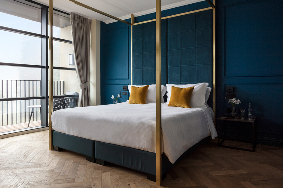 SCHLOSS Roxburghe suite with gold four poster bed and dark teal walls.