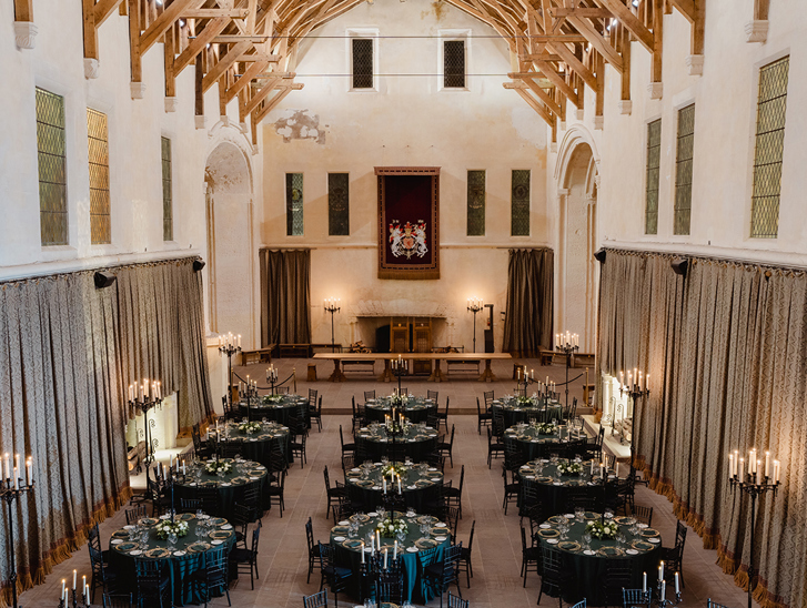 Overhead view of Stirling Castle Great Hall set for a luxury wedding dinner with dark green table linens, round tables and elegant candlelight.