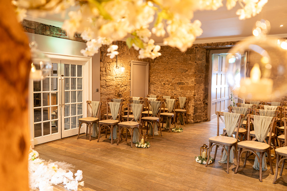 Intimate wedding ceremony setup at Strathaven Hotel with rustic chairs and stone walls creating a romantic indoor ceremony space.