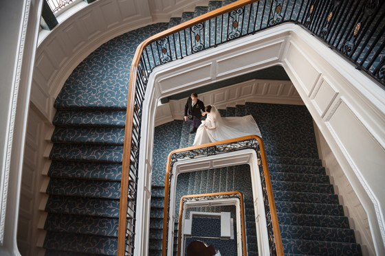 verhead view of bride and groom walking down The Balmoral Hotel atrium staircase on wedding day