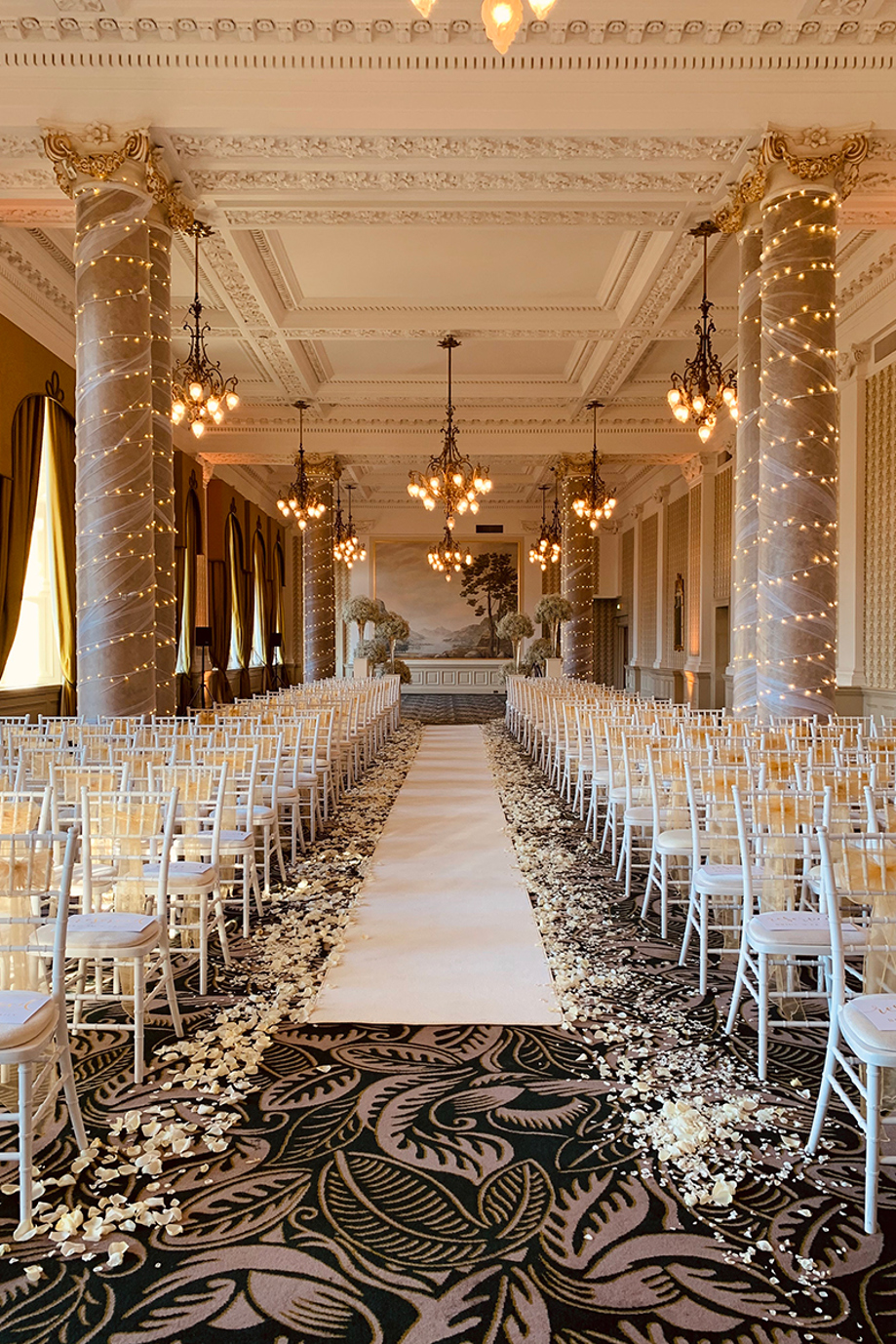 Wedding ceremony aisle at The Balmoral Hotel with fairy lights wrapped around columns and white chairs