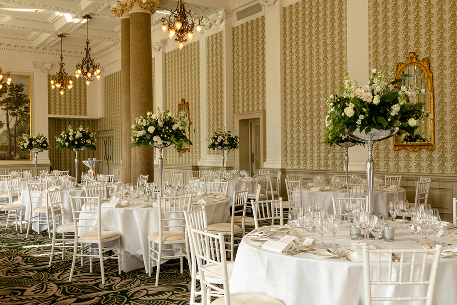 Wedding reception setup at The Balmoral Hotel Edinburgh with round tables, white Chiavari chairs and tall floral centrepieces