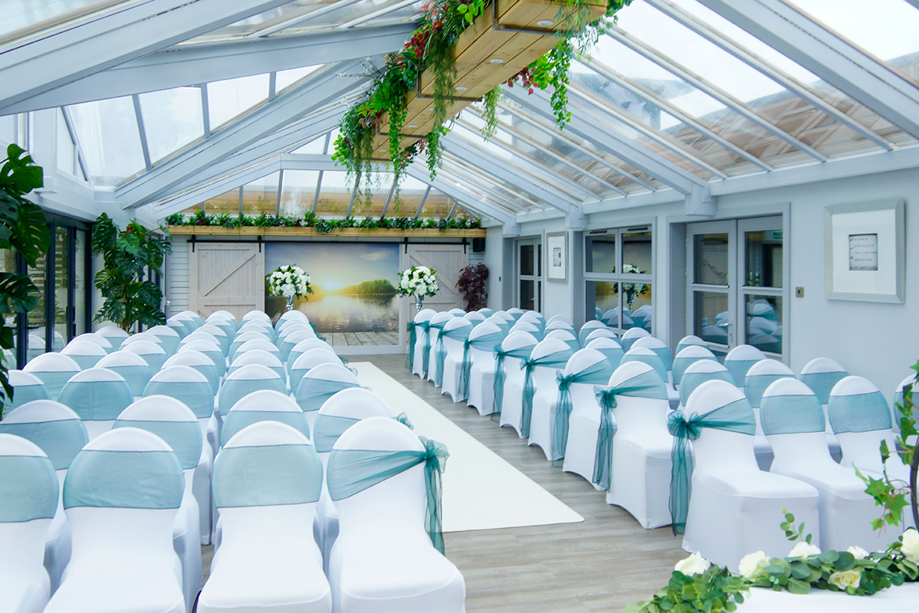 Ceremony room decorated with light blue chair bows and floral trees at altar