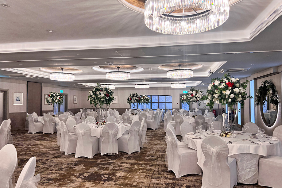 Wedding meal set up with large bouquets of white and red flowers in middle of tables