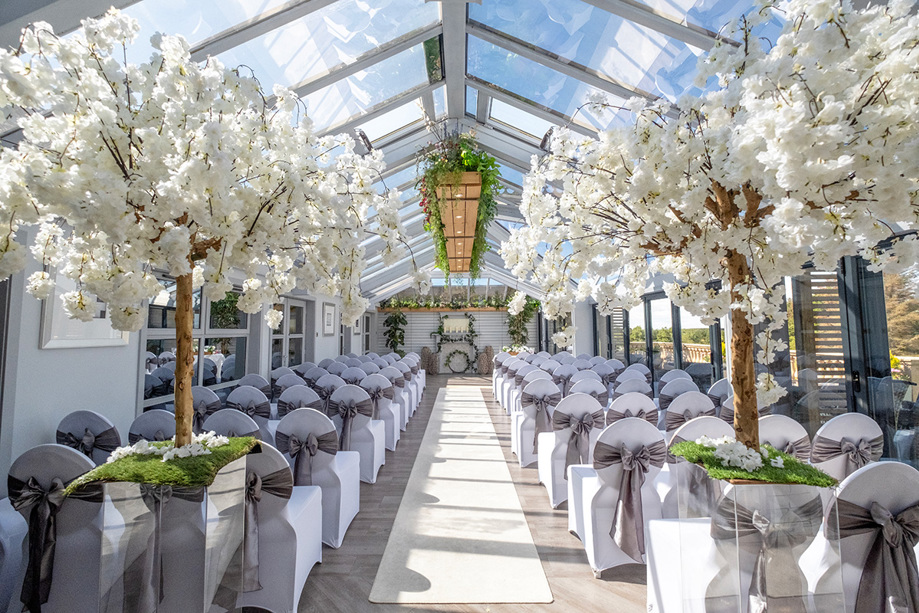 Light-filled ceremony room with white floral trees on acrylic stands