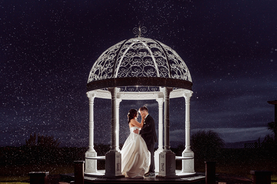 Starry sky image of a bride and groom embracing beneath white wedding bandstand in the private gardens of The Waterside Hotel