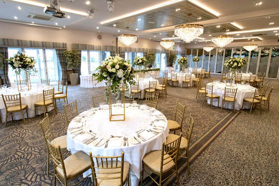 Wedding meal setup at The Waterside Hotel with gold chiavari chairs and gold centrepieces with flowers