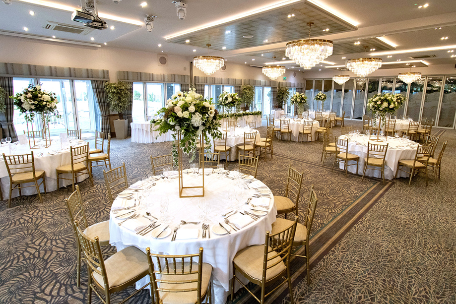 Wedding meal setup at The Waterside Hotel with gold chiavari chairs and gold centrepieces with flowers