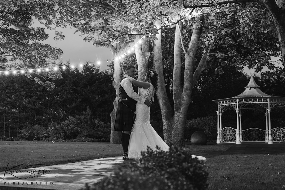 Black and white image of newlyweds dancing under festoon lights at Carlton Hotel in Prestwick
