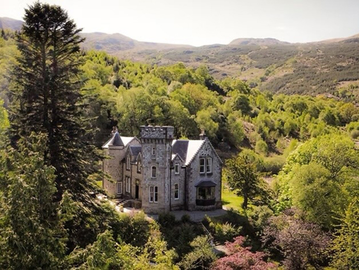 Aerial view of Castle Craigard surrounded by woodland and Scottish hills