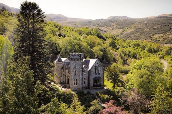 Aerial view of Castle Craigard surrounded by woodland and Scottish hills