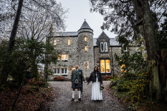 Bride and groom holding hands outside Castle Craigard stone wedding venue