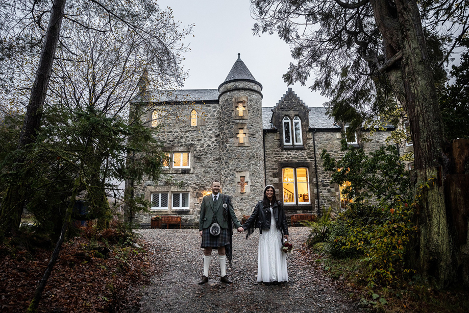 Bride and groom holding hands outside Castle Craigard stone wedding venue