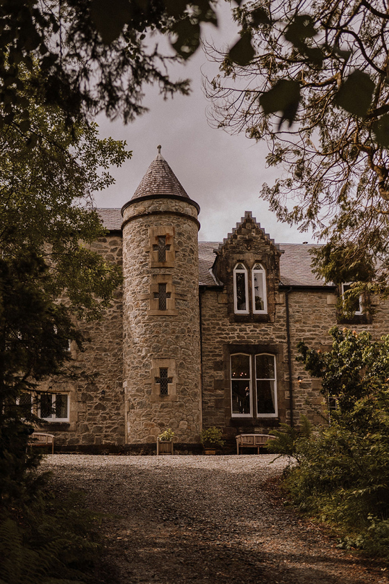 Exterior of Castle Craigard with stone turret and woodland surroundings