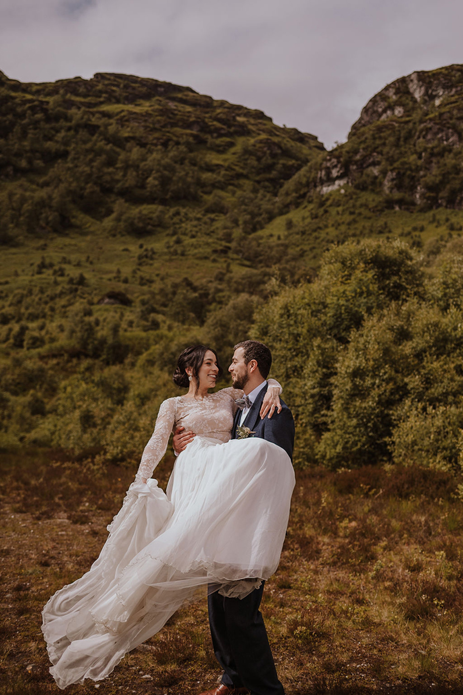 Groom carrying bride during hillside wedding portraits at Castle Craigard