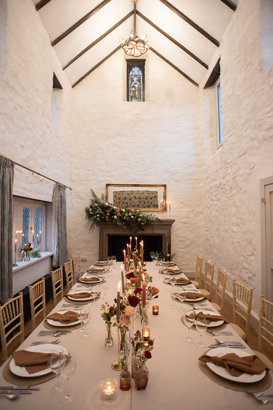 Long table wedding meal in Castle Craigard converted chapel with candles and flowers