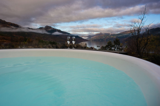Castle Craigard hot tub overlooking Loch Goil with champagne glasses and mountain views