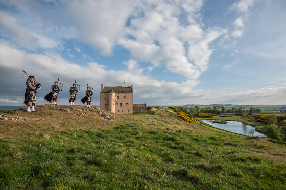 Bagpipers performing outside Fenton Tower with views across the East Lothian landscape