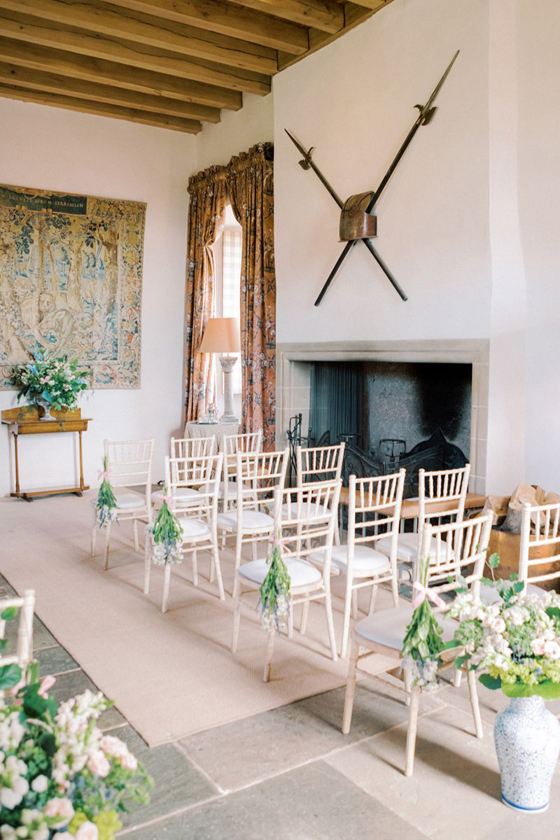 Indoor wedding ceremony setup with white chairs and floral aisle decor inside a historic Scottish tower house