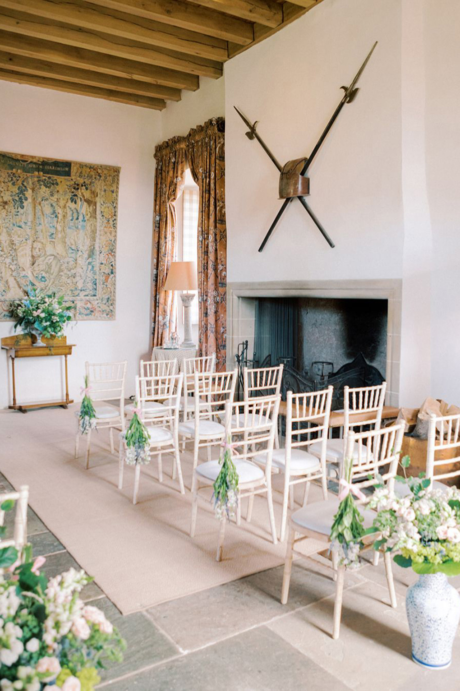 Indoor wedding ceremony setup with white chairs and floral aisle decor inside a historic Scottish tower house
