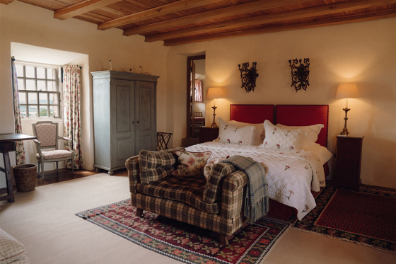 Traditional guest bedroom at Fenton Tower with exposed beams, antique furniture and countryside views