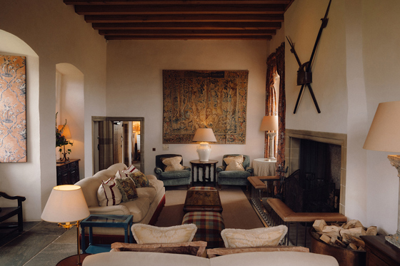 Elegant sitting room inside Fenton Tower featuring historic tapestries, open fireplace and relaxed lounge seating