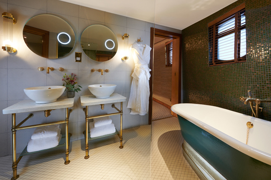 Skerryvore Suite bathroom with double sink and teal bath with gold accents throughout.