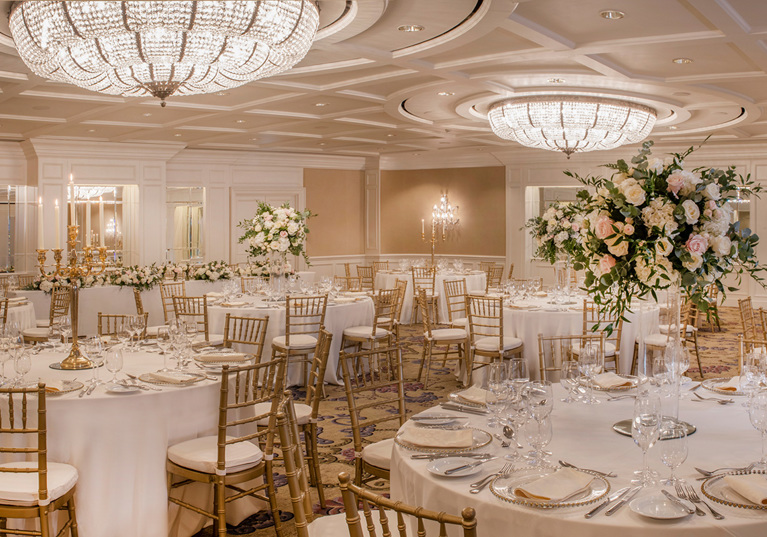 Ballroom wedding meal set up with flowers and gold accents