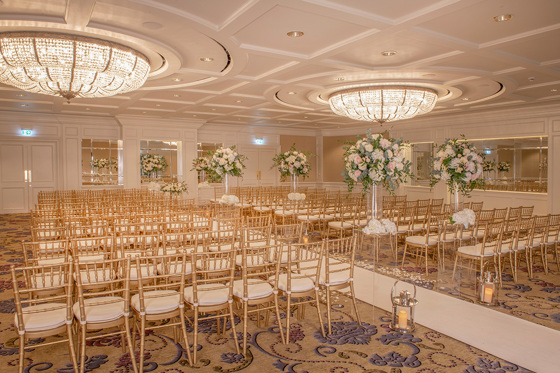 Ceremony room decorated with large bouquets of flowers and candle lanterns