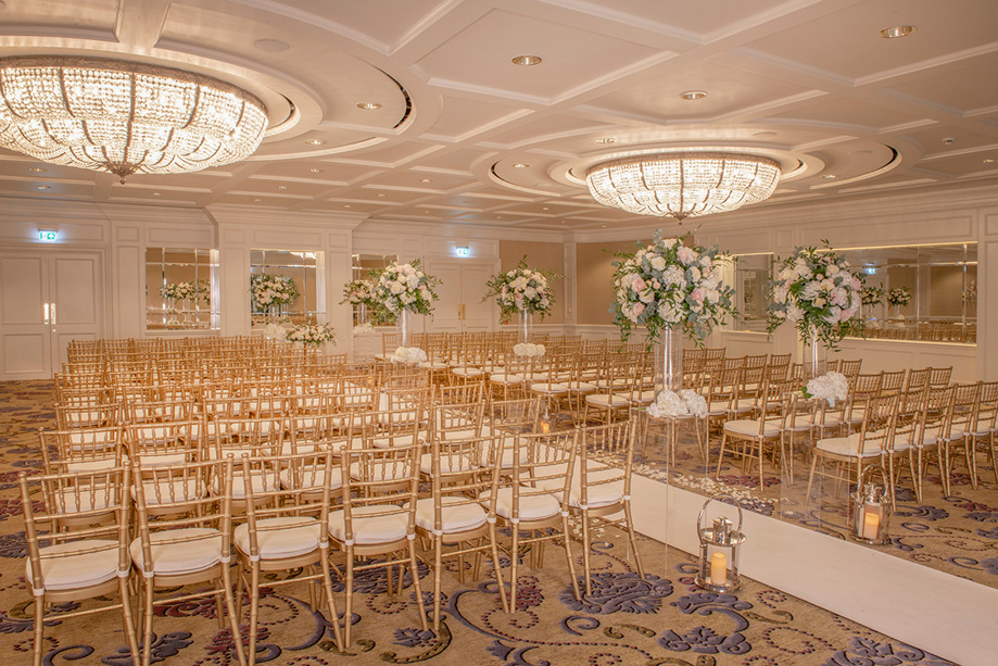 Ceremony room decorated with large bouquets of flowers and candle lanterns
