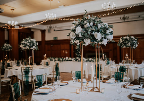 Wedding breakfast setup with green and white floral centrepiece 