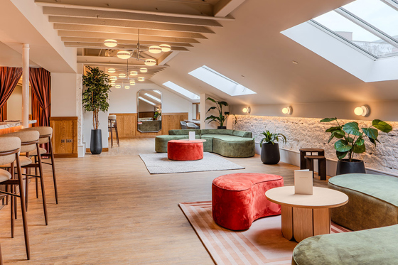 The Parlour at The Exchange in Glasgow, with sky lights flooding the room with light, green and red seating areas, and green plants.