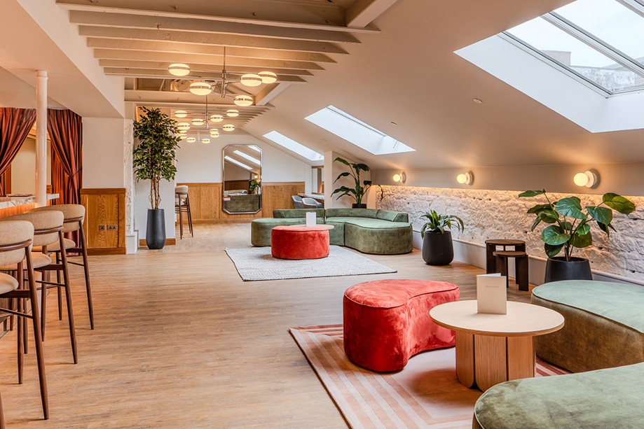 The Parlour at The Exchange in Glasgow, with sky lights flooding the room with light, green and red seating areas, and green plants.