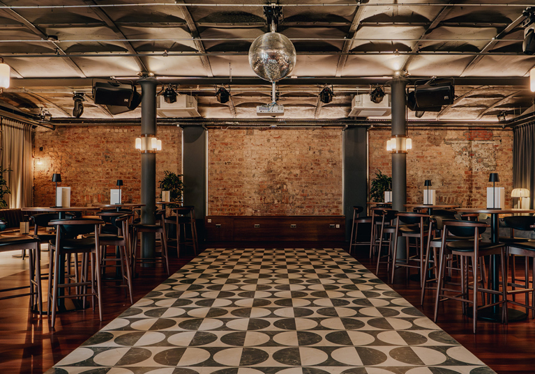 Print Room at The Exchange in Glasgow, with a disco ball, exposed bricks, black and white tiled dancefloor and barstools.
