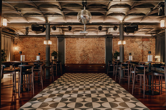 Print Room at The Exchange in Glasgow, with a disco ball, exposed bricks, black and white tiled dancefloor and barstools.