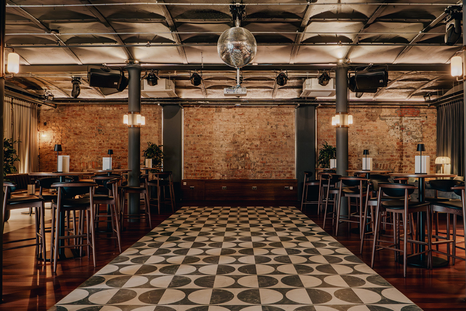 Print Room at The Exchange in Glasgow, with a disco ball, exposed bricks, black and white tiled dancefloor and barstools.