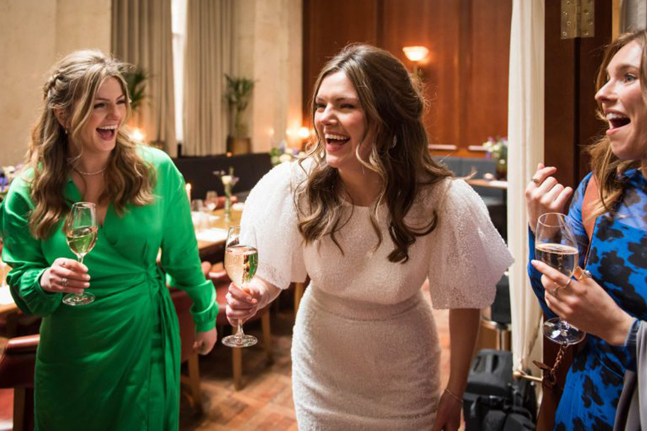 Bride and guests sharing a toast and laughing during a wedding reception at Hawksmoor Edinburgh.