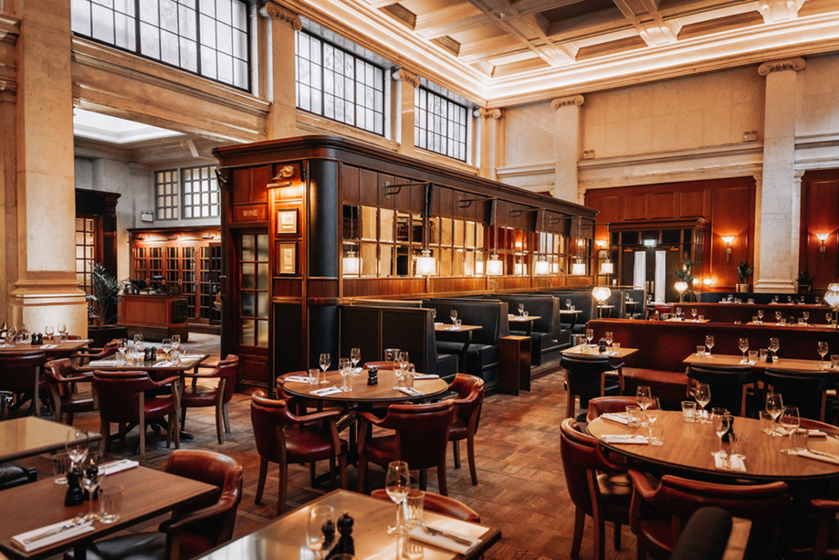 Hawksmoor Edinburgh’s grand dining room featuring high ceilings, large windows, leather seating and tables set for guests.