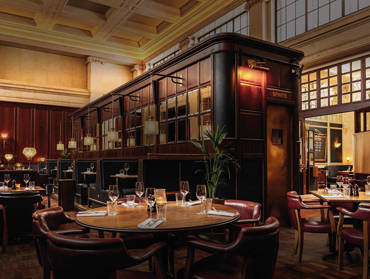 Image of the bar in food-focused venue Hawksmoor Edinburgh, with dark wood tones and warm lighting.