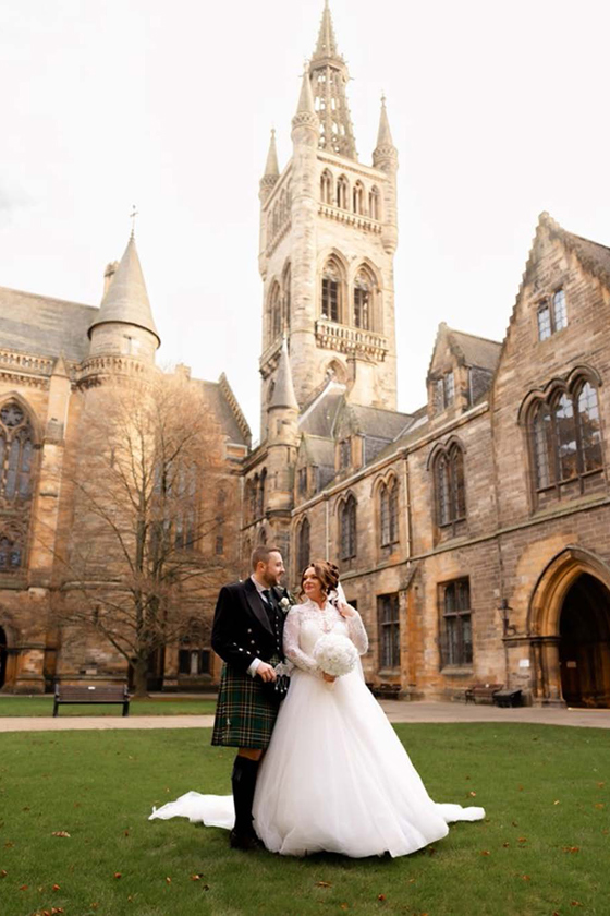 Bride and groom gaze into each others eyes on the grass outside the University of Glasgow.