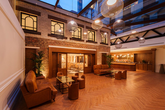 the courtyard at the collector's hall at night with bar in the background and cleared floor space with herringbone flooring