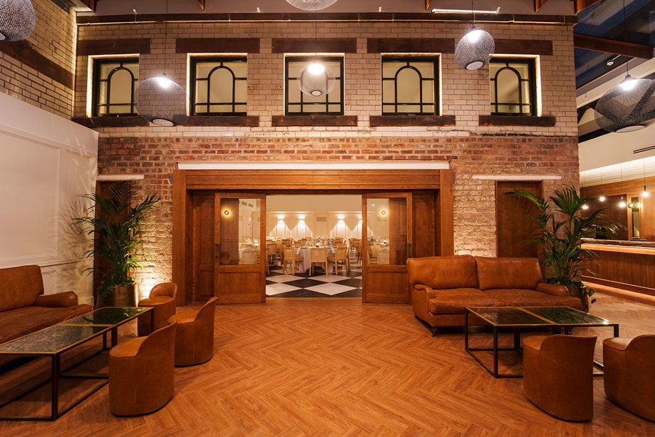 The Courtyard at The Collector's Hall with an all-weather glass canopy, herringbone flooring and tan leather couches