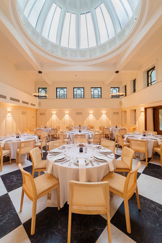The Collector's Hall set up for a wedding dinner with round tables and wooden rattan chairs
