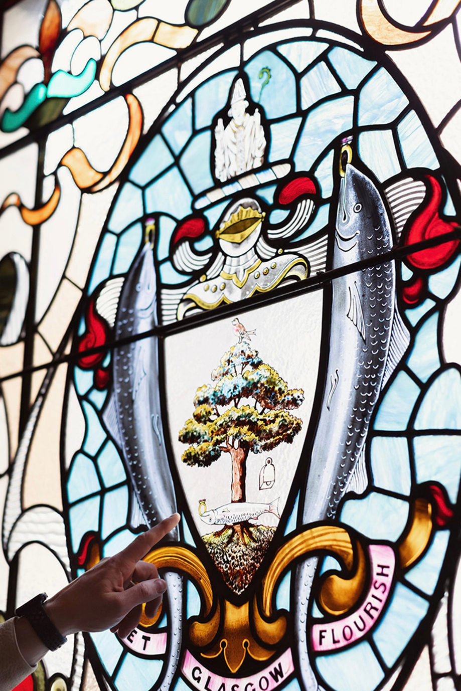 Hand points to detailing on stained glass windows at The Collector's Hall.