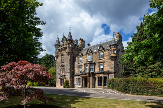 Exterior of The Scott Hotel in Edinburgh, showing its turrets with blue skies in background.
