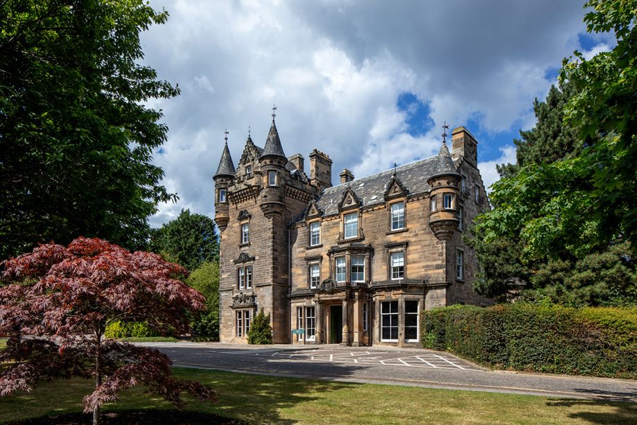 Exterior of The Scott Hotel in Edinburgh, showing its turrets with blue skies in background.